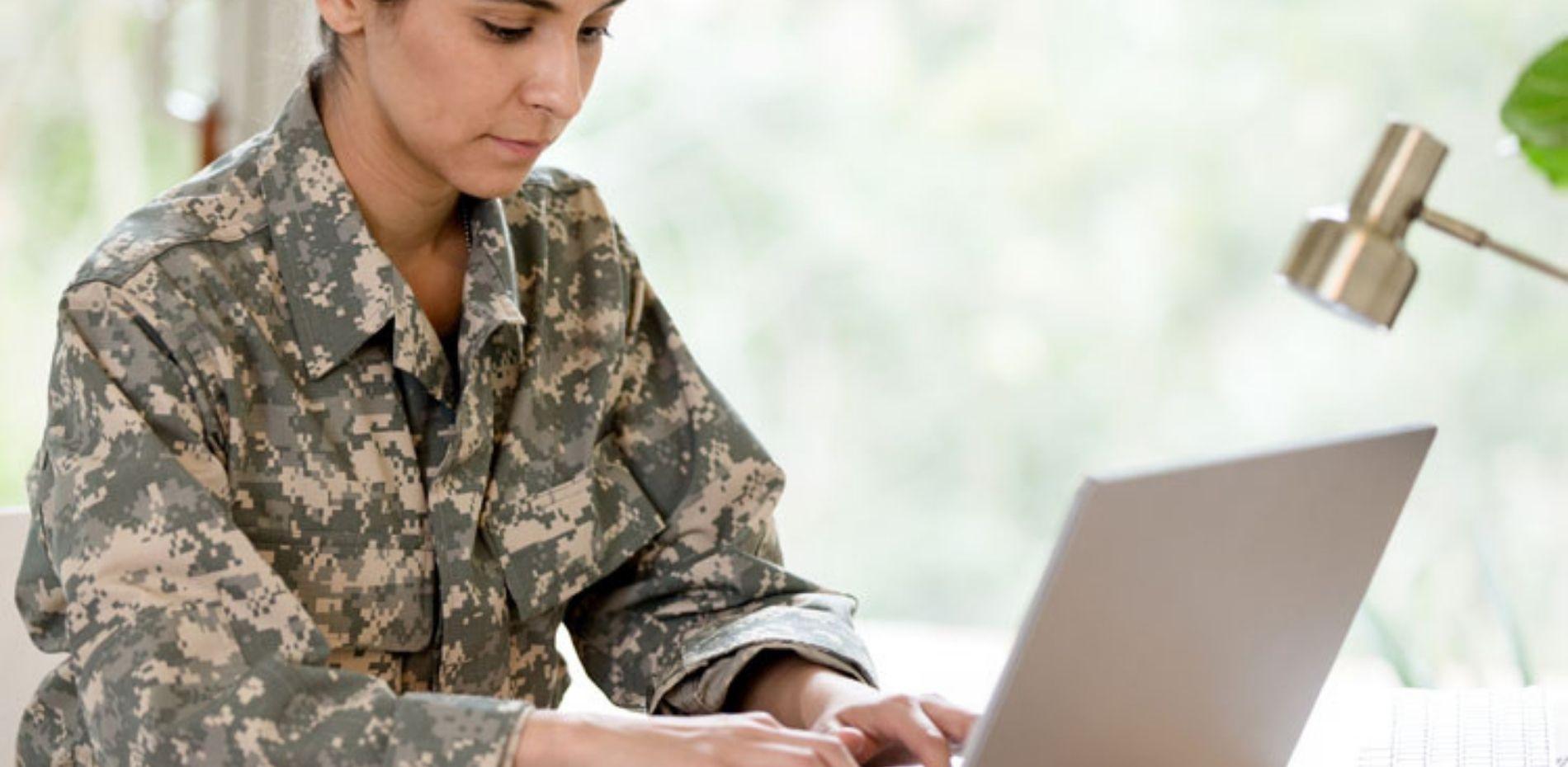 Woman in military uniform working on laptop